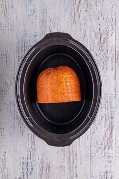 a loaf of bread in a crock pot on a white wooden table top view from above