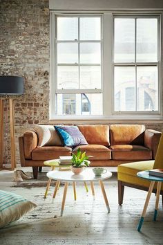 a living room with two couches and a coffee table in front of a brick wall