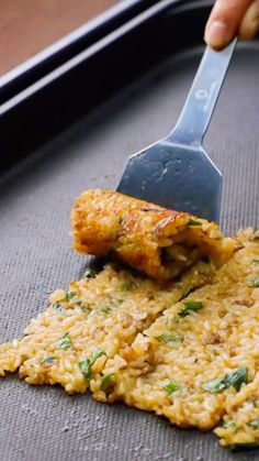 someone is using a spatula to scoop food out of a baking pan with rice