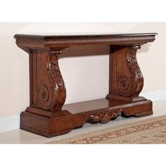 a wooden table with carved carvings on the top and bottom shelf, in front of a beige wall