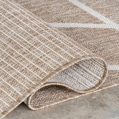 an area rug with beige and white squares on it, in the middle of a room