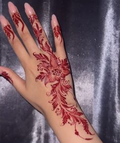 a woman's hand with red henna on it and flowers painted on the palm