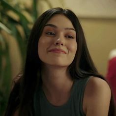 a woman with long brown hair and blue eyes smiles at the camera while sitting on a couch