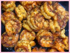 cooked shrimp with garlic and herbs in a pink square frame on a black plate, ready to be eaten