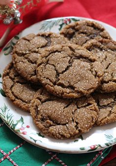 some cookies are on a white plate next to a red and green table cloth with christmas decorations