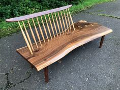 a bench made out of wooden sticks sitting on top of a cement ground next to grass