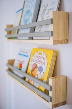 two wooden bookshelves holding children's books on the side of a wall