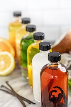 several bottles filled with liquid sitting on top of a table next to sliced lemons