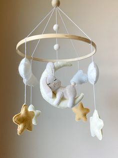 a teddy bear is sleeping on the moon mobile with stars around it and a ball hanging from the ceiling