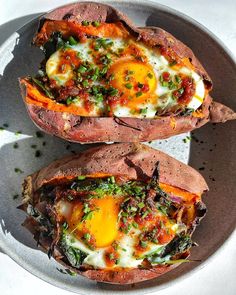 two baked sweet potatoes on a plate topped with an egg and spinach toppings