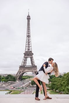 a man and woman kissing in front of the eiffel tower, paris france