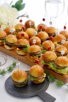 mini burgers with toothpicks on them are arranged on a tray for an appetizer