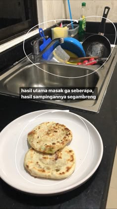 two flat breads sitting on top of a white plate next to a silver sink