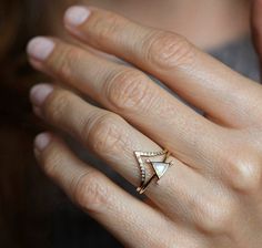 a close up of a person wearing a ring with an arrow design on it's middle finger