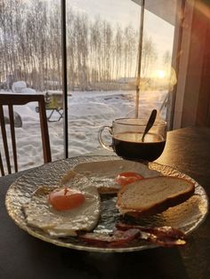 a breakfast plate with eggs, toast and bacon next to a cup of coffee on a table