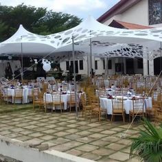 tables and chairs are set up for an outdoor event with white tent coverings over them