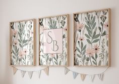 two framed pictures hanging on the wall with bunting and flowers in front of them