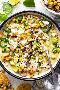 a white bowl filled with chicken, corn and rice soup next to crackers on the side