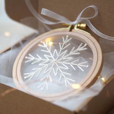 an ornament in a box with string lights on the inside and snowflake