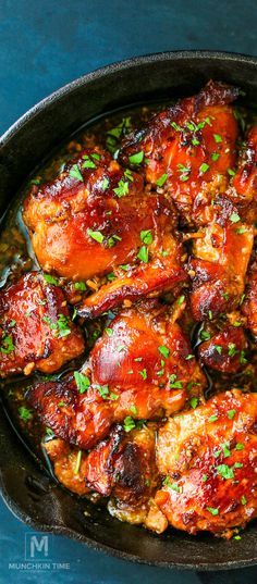 a skillet filled with meat covered in sauce and garnished with parsley