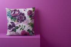 a floral pillow sitting on top of a purple shelf