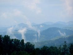 the mountains are covered in clouds and trees