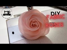 a pink flower sitting on top of a sewing machine with the words diy fabric roses