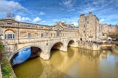 an old stone bridge over a river next to tall buildings