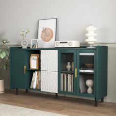 a green cabinet with books and pictures on the top is next to a potted plant