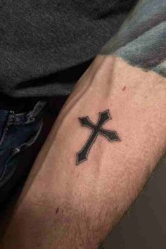 a man's arm with a black cross tattoo on the left side of his arm