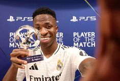 a young man holding up a trophy in front of a blue wall with the words player of the match written on it