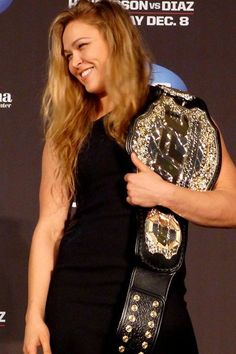 a woman holding a wrestling belt and smiling