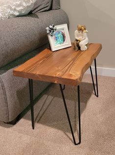 a wooden table sitting on top of a carpeted floor next to a gray couch