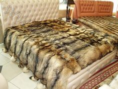 a bed that has been made with fur and pillows on top of it in a room