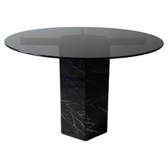 a round glass table with black marble base