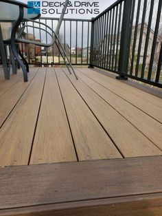 a wooden deck with metal railings next to a large sign that reads decks and drive solutions