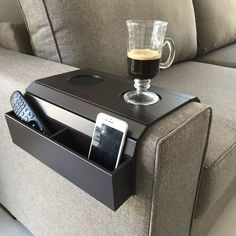 a coffee cup sitting on top of a table next to a cell phone and remote control