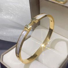 These Are Highly Polished Fashion Titanium Stainless Steel Gold Plated Pieces That Will Last A Lifetime. It Is Corrosion And Scratch Resistant And Hypoallergenic. The Bangle Is An Oval Shape That Sits Perfectly On The Wrist With The H Or Always On Top. The H/Front Are Set In A White Mother Of Pearl Style Tone. Outside Circumference Of Bracelet Is Approximately 19cm Brand New Gold Tone Color White Metal Bangle As A Gift, White Metal Bangle Gift, Adjustable White Metal Bangle, White Metal Bangle Jewelry, White Stainless Steel Jubilee Bracelet, White Stainless Steel Bangle Bracelets, White Stainless Steel Bangle Bracelet, Adjustable White Bangle, White Elegant Metal Bangle