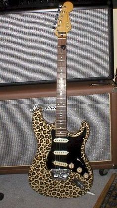 an electric guitar sitting on top of a leopard print case