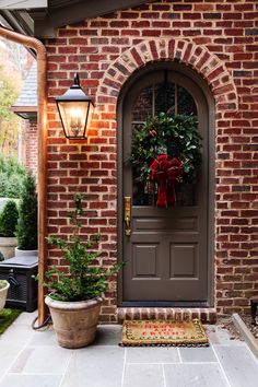 the front door is decorated for christmas with wreaths and potted plants