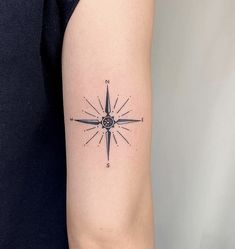 a black and white compass tattoo on the arm