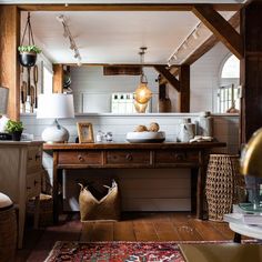 a room with wooden floors, white walls and an old fashioned desk in the center