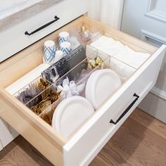 an open drawer with dishes in it