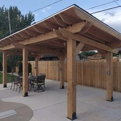 an outdoor covered patio with tables and chairs next to a fenced in backyard area