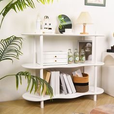 a white shelf with books and other items on it in a room next to a potted plant