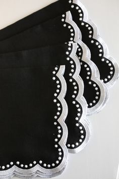 four black and white placemats on top of each other, one with scalloped edges