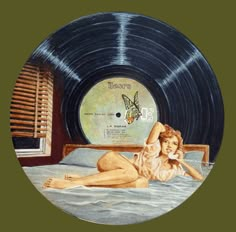 a woman laying on top of a bed next to a record