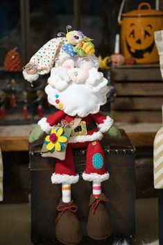 a santa clause doll sitting on top of a suitcase