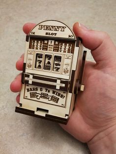 a person holding a wooden toy machine in their left hand with the words penny's slot on it