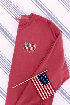 Most sizes and colors are available to ship next day! I love this USA shirt. God Bless the USA! These vintage inspired embroidered American flags are perfect for showing your patriotism this summer at your Fourth of July celebrations! Embroidered on your choice of a Comfort Colors tank, tee, long sleeve, crewneck sweatshirt, or quarter zip. 4tb Of July, Usa Graphic Tee, American Flag Embroidery, Long Sleeve Cotton Tops For 4th Of July, Cotton Long Sleeve Top For 4th Of July, Long Sleeve American Style Cotton Sweatshirt, Long Sleeve Tops For 4th Of July, American Style Cotton Long Sleeve Sweatshirt, Cotton Crew Neck Sweatshirt With Flag Print